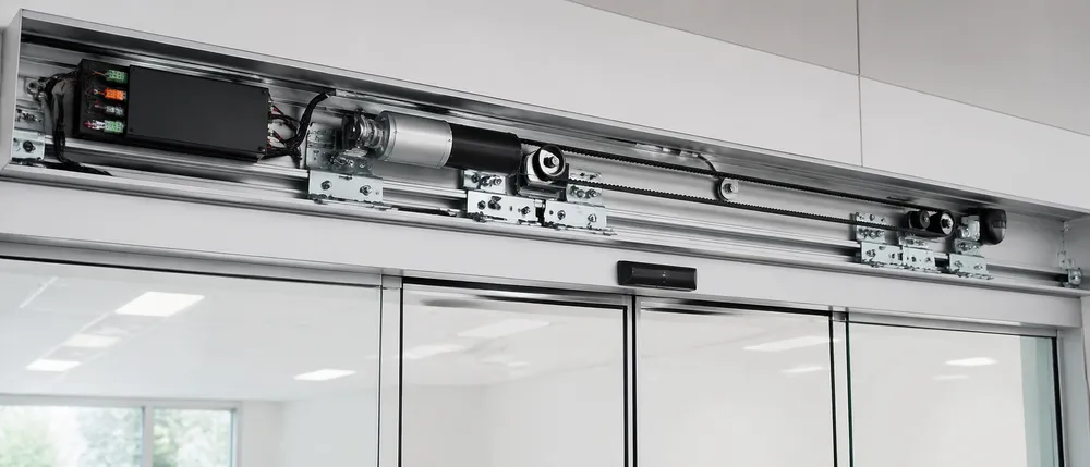 Automatic sliding commercial door drive unit with brushless DC motor, belt transmission, and overhead sensor package installed
