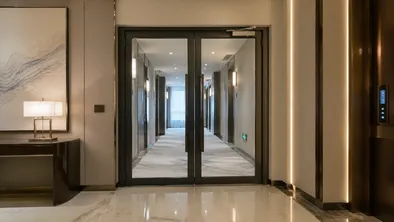 Glass fire door at hotel lobby-to-corridor transition with premium finish