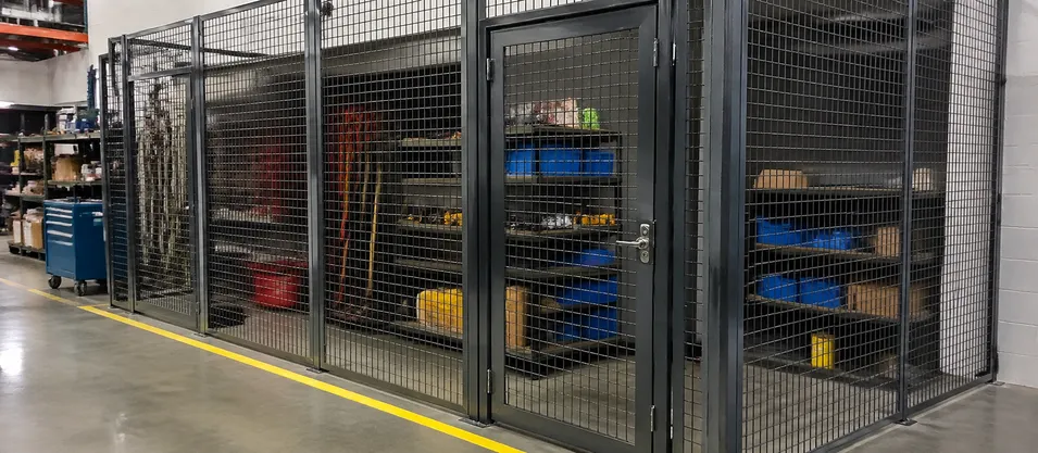Wire mesh security door on an industrial tool crib in a manufacturing facility with heavy-duty continuous hinge hardware