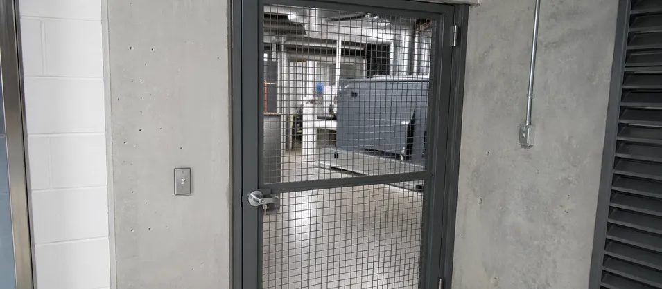 Wire mesh security door on a utility mechanical room showing ventilation and visibility function alongside access control