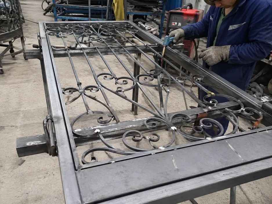 Hand-bent wrought iron scrollwork welded onto structural steel door frame before powder coat finishing