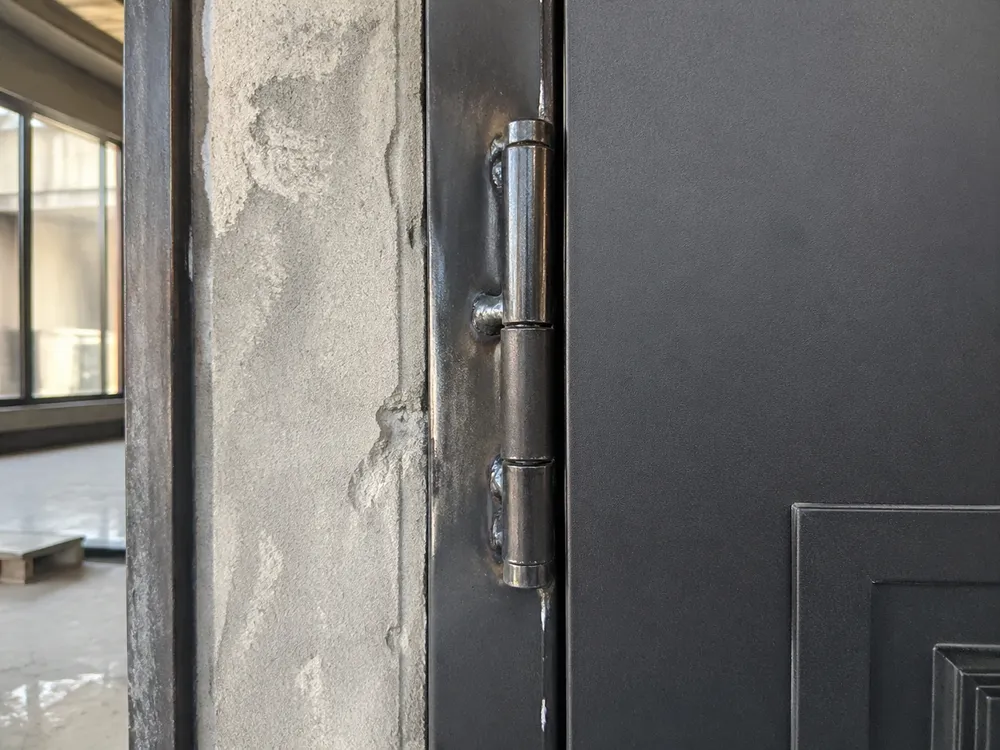 Heavy-duty weld-in hinge detail on iron door installation